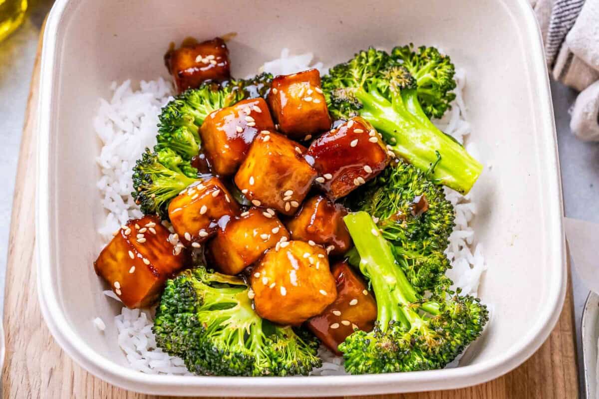 a white bowl with teriyaki tofu over white rice and broccoli.