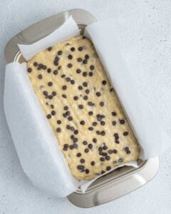 Banana bread batter is added to a pan.