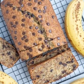 banana bread on a wire rack with half the bread sliced through.