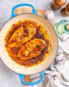 2 Cajun chicken breasts cooked in a skillet.