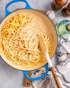 adding in the cooked pasta with the sauce in the pan and tossing together.