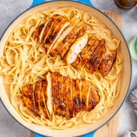 a skilled with creamy linguine topped with cajun chicken.