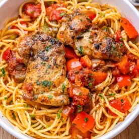 chicken cacciatore over spaghetti in a bowl.