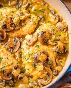 A skillet containing chicken scallopini with mushrooms and sauce.