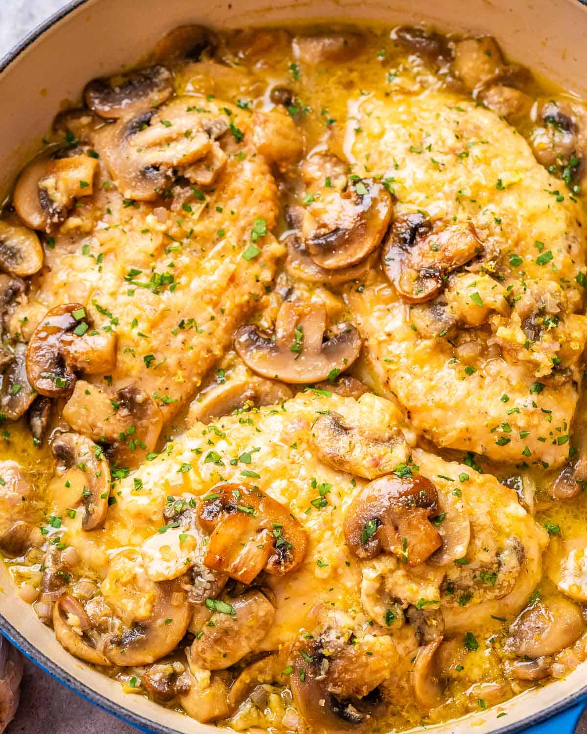 chicken breasts in a lemon garlic mushroom sauce in a skillet.