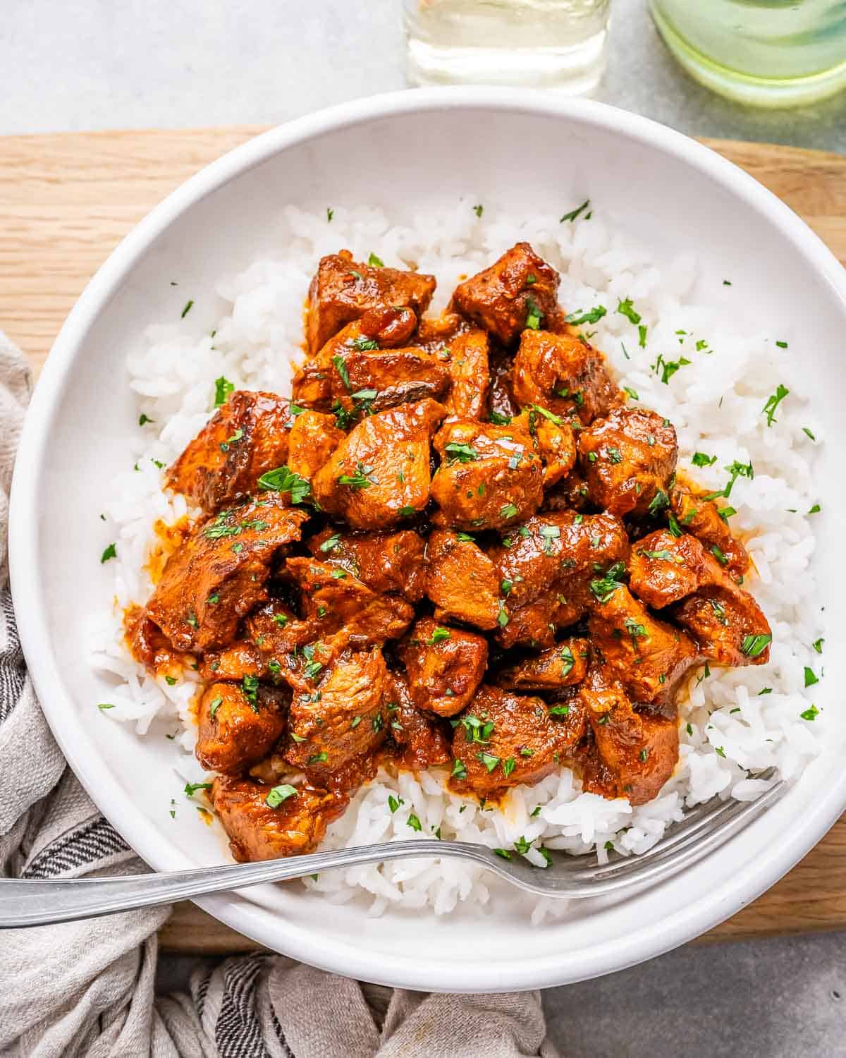 A white bowl of chicken vindaloo with rice.