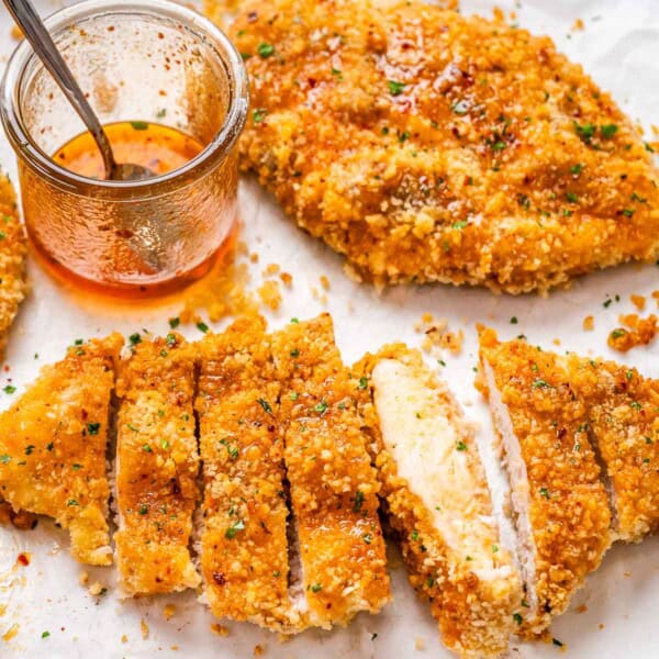 sliced crispy chicken cutlets topped with honey on a sheet pan.