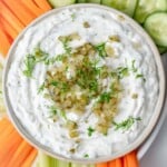 a bowl filled with dill pickle dip made with chopped pickles and greek yogurt and served with fresh veggies.