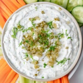a bowl filled with dill pickle dip made with chopped pickles and greek yogurt and served with fresh veggies.