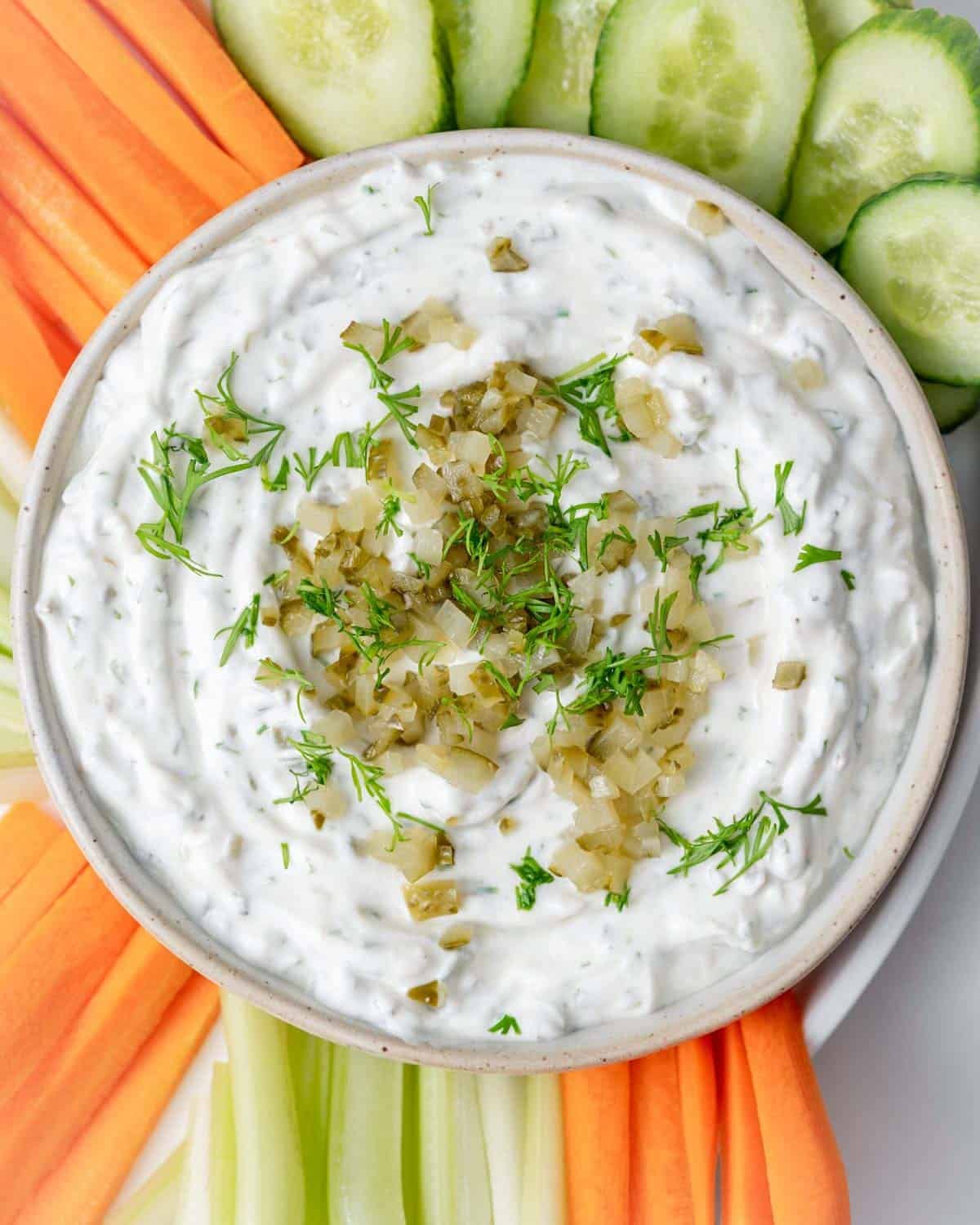 a bowl with dill pickle dip surrounded by sliced veggies.