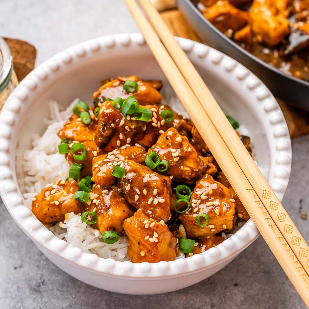 a bowl with hoisin chicken served over a bowl of rice.