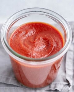 A jar of taco sauce on a grey napkin.
