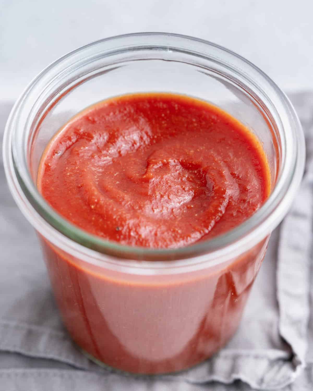 A jar of taco sauce on a grey napkin.