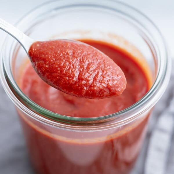 a spoonful of taco sauce over a jar full of the sauce.