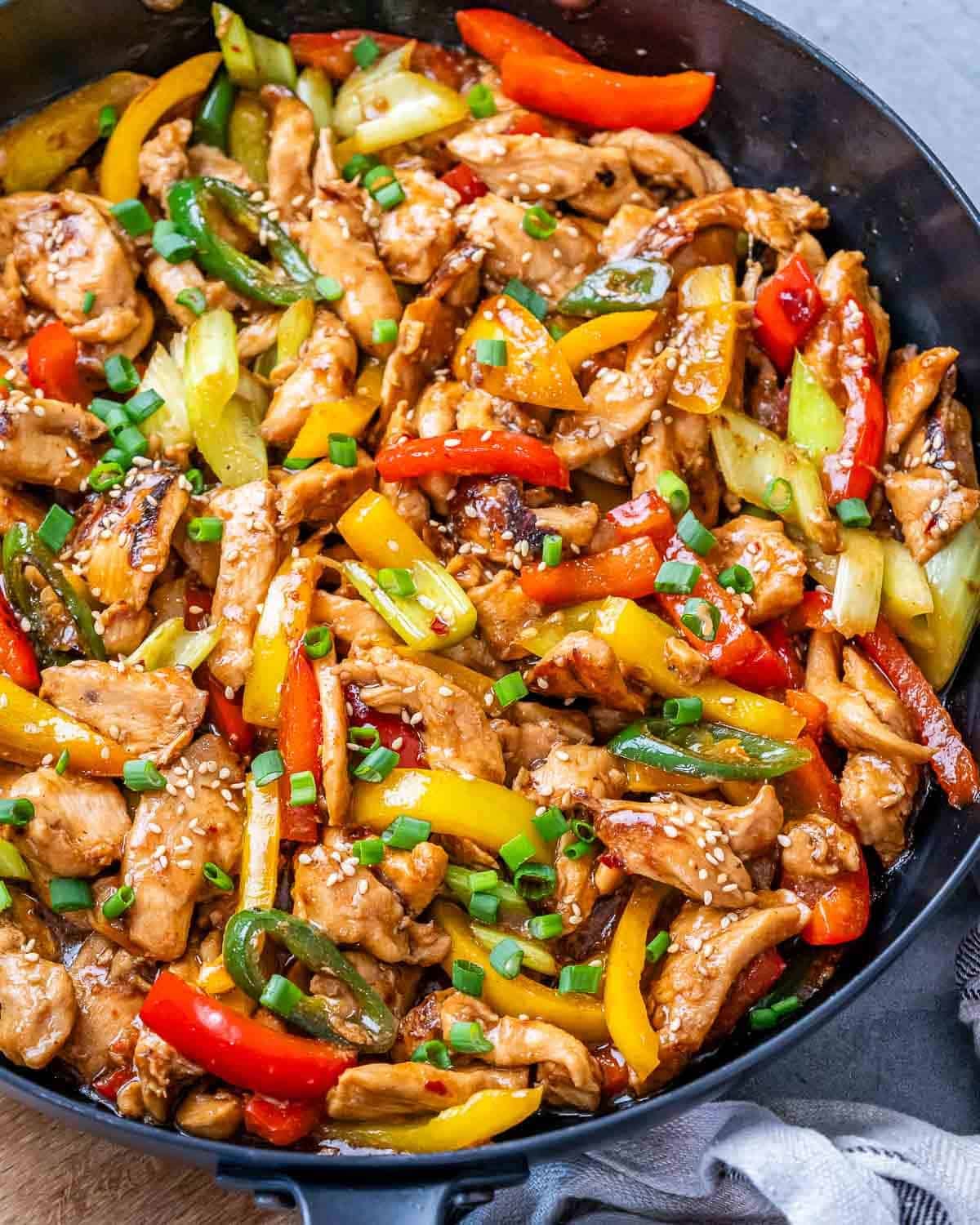 A skillet with sliced chicken, bell peppers and celery in Hunan sauce.