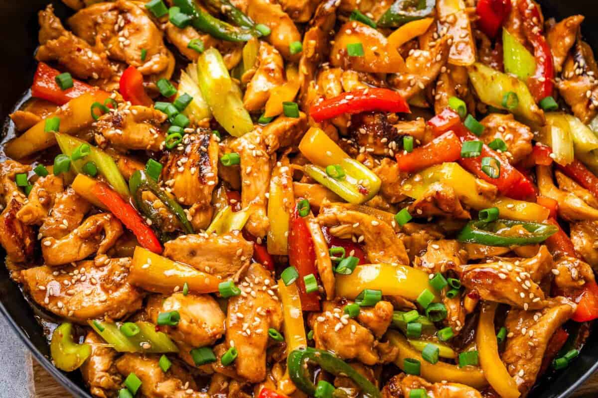 hunan chicken in a skillet with veggies.