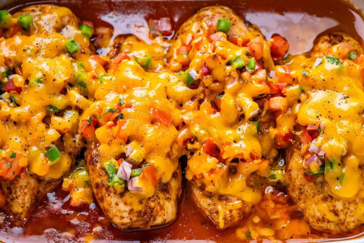 chicken breasts baked in a dish, topped with fresh salsa, and shredded cheese.