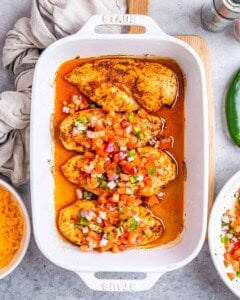 fresh salsa added over baked chicken in a dish.