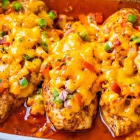 chicken breasts baked in a dish topped with salsa and topped with melted cheddar cheese.