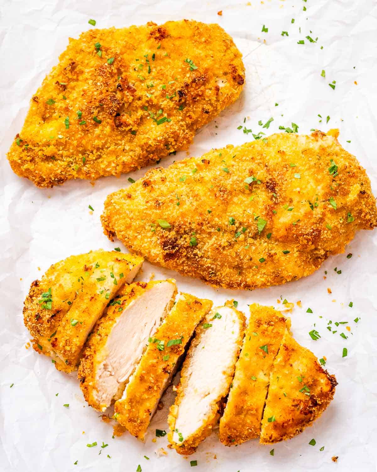 3 crispy chicken breasts laid one with one of them sliced.