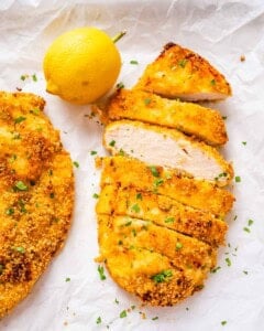 Crispy shake and bake chicken breast on parchment paper with a lemon.