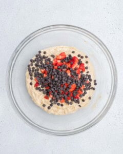 strawberries and chocolate chips added over the batter in a bowl.