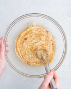 whisking yogurt, mashed banana, sugar, butter, and egg in a bowl.