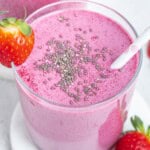 a cup full of smoothie that purple looking, topped with a sprinkle of chia seeds with a straw in the cup.