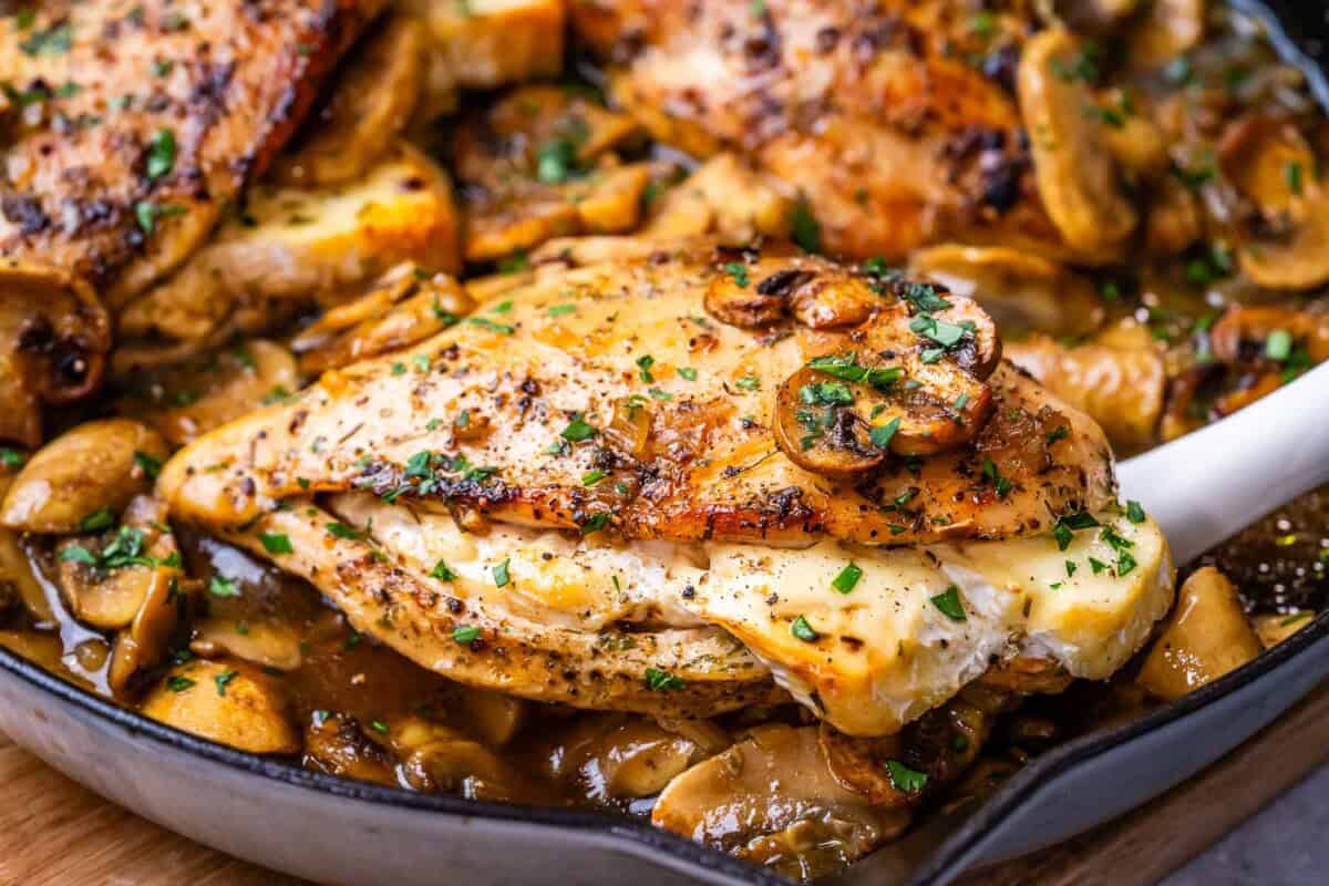 grabbing a stuffed chicken from the skillet.