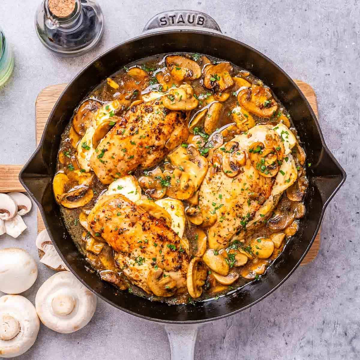 a skillet with stuffed chicken breasts with cheese and mushroom sauce.