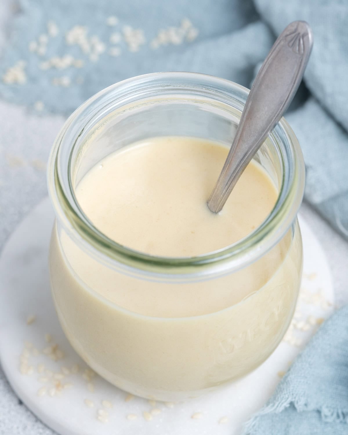 a jar with tahini dressing and a spoon in it.