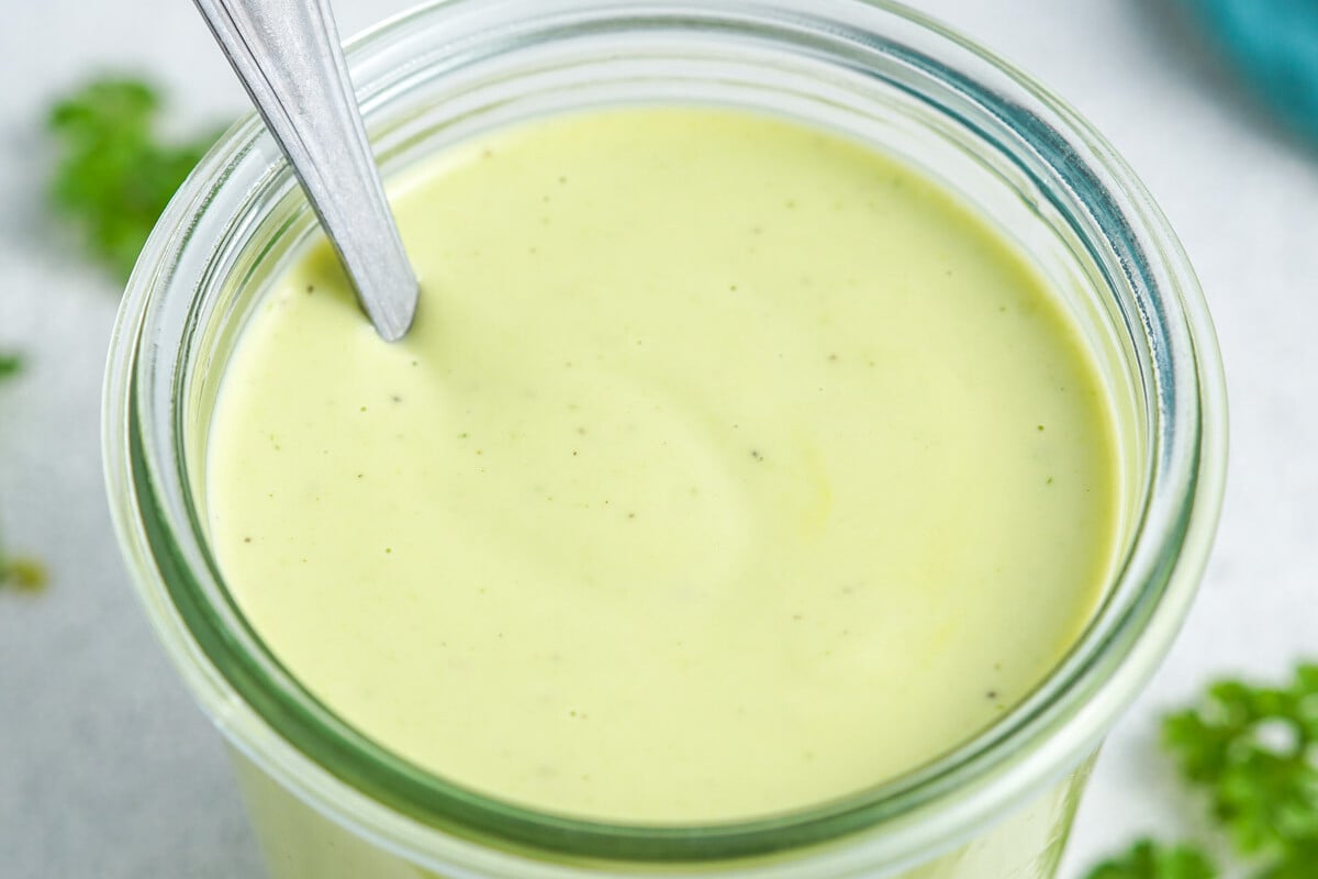 green looking ranch dressing in a jar with a spoon in the jar.