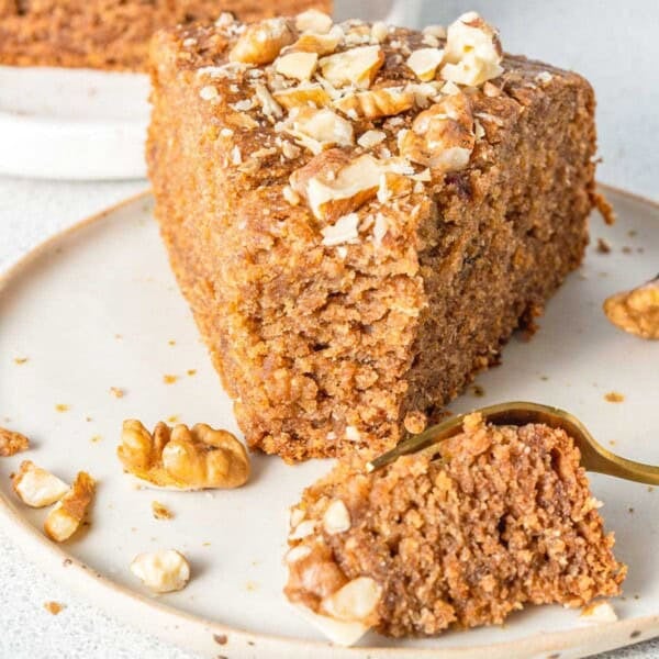 a slice of date cake topped with walnuts on a plate.