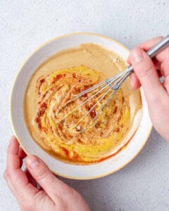 hand whisks the honey mustard sauce.