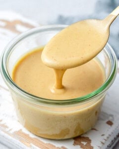 honey mustard sauce in a jar, with spoon dipped into the sauce.