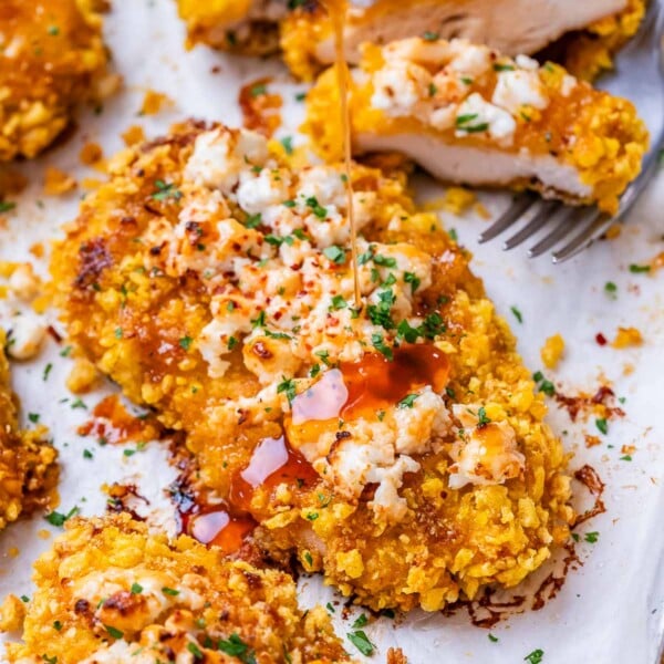 honey being drizzled over crispy chicken topped with feta cheese.
