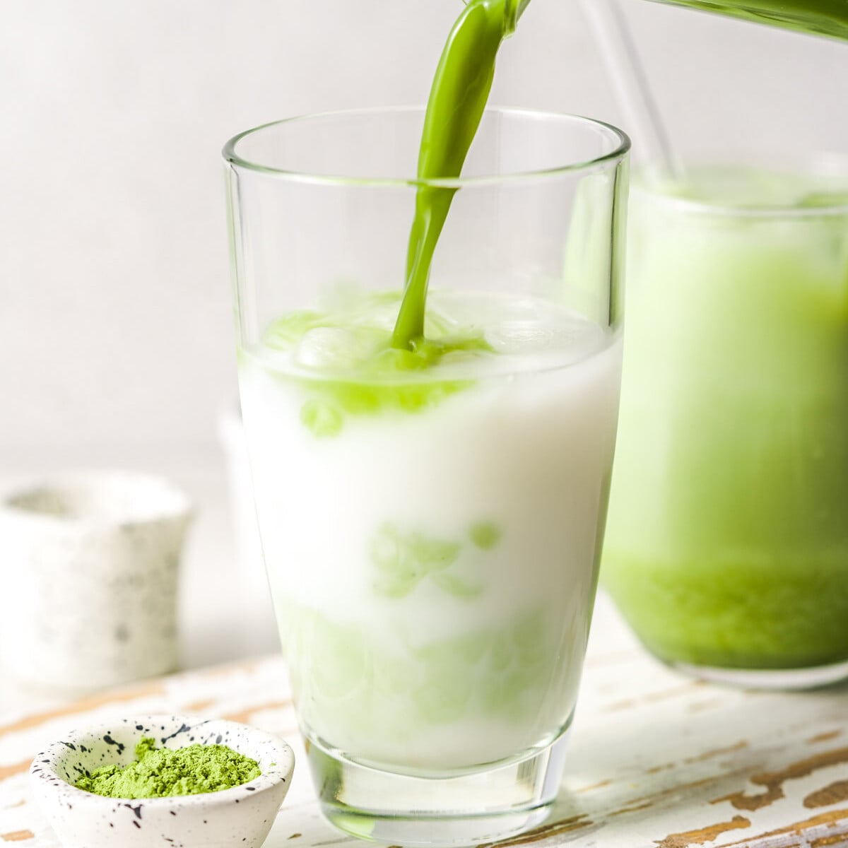 matcha being poured into a cup of milk.