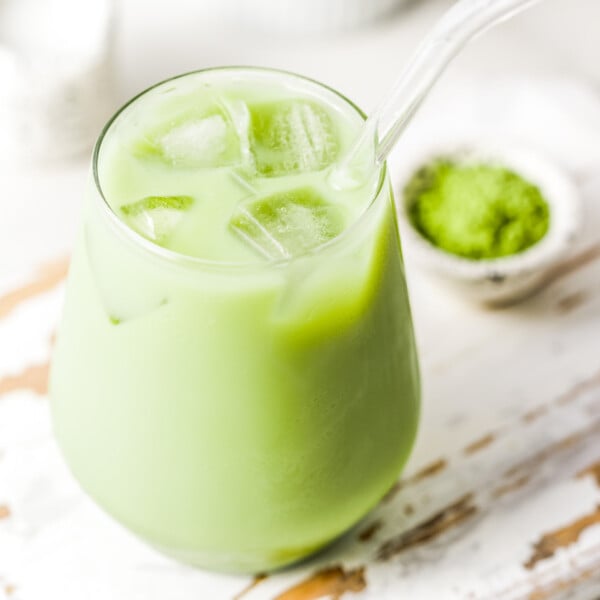 a cup with an iced matcha latte with a glass straw in the cup.