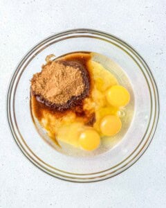 mashed banana, eggsm sugar, and oil, added into a bowl.