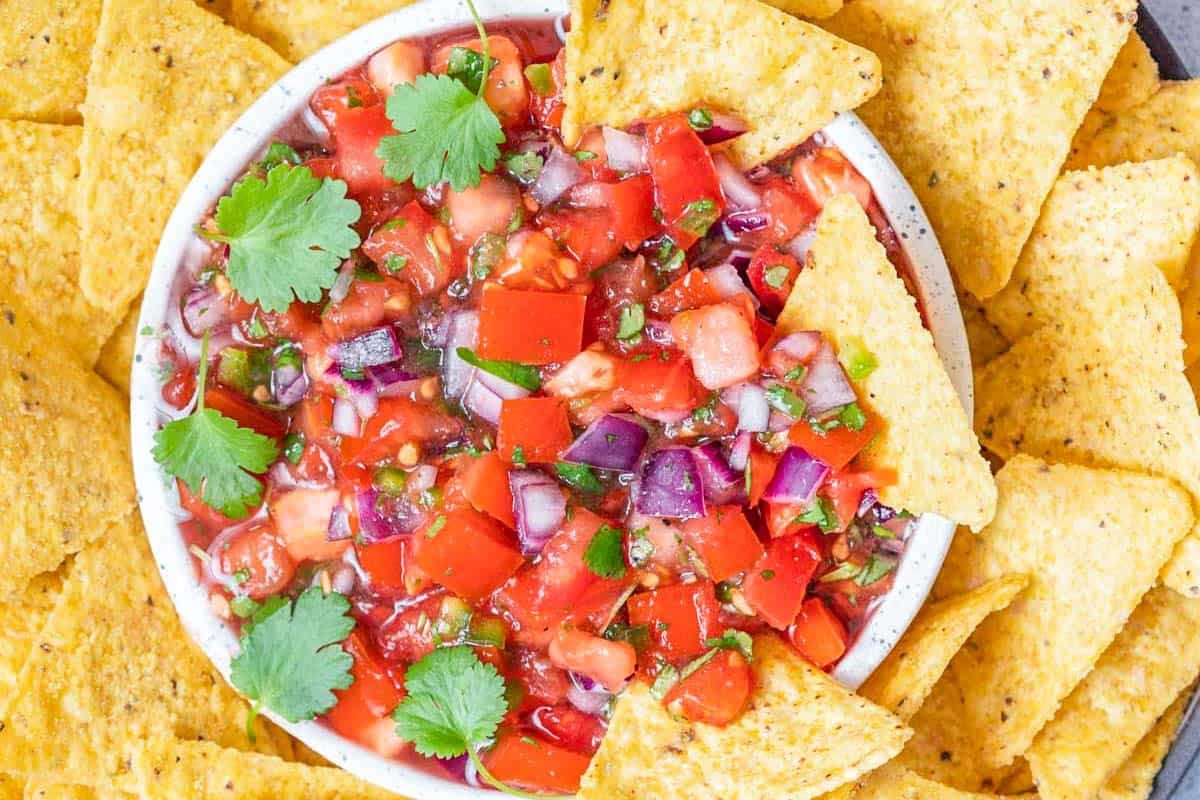 a bowl with pico de gallo and chips around the bowl.