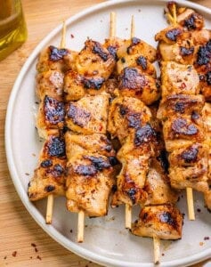 Bang Bang Chicken skewers on a round white plate.