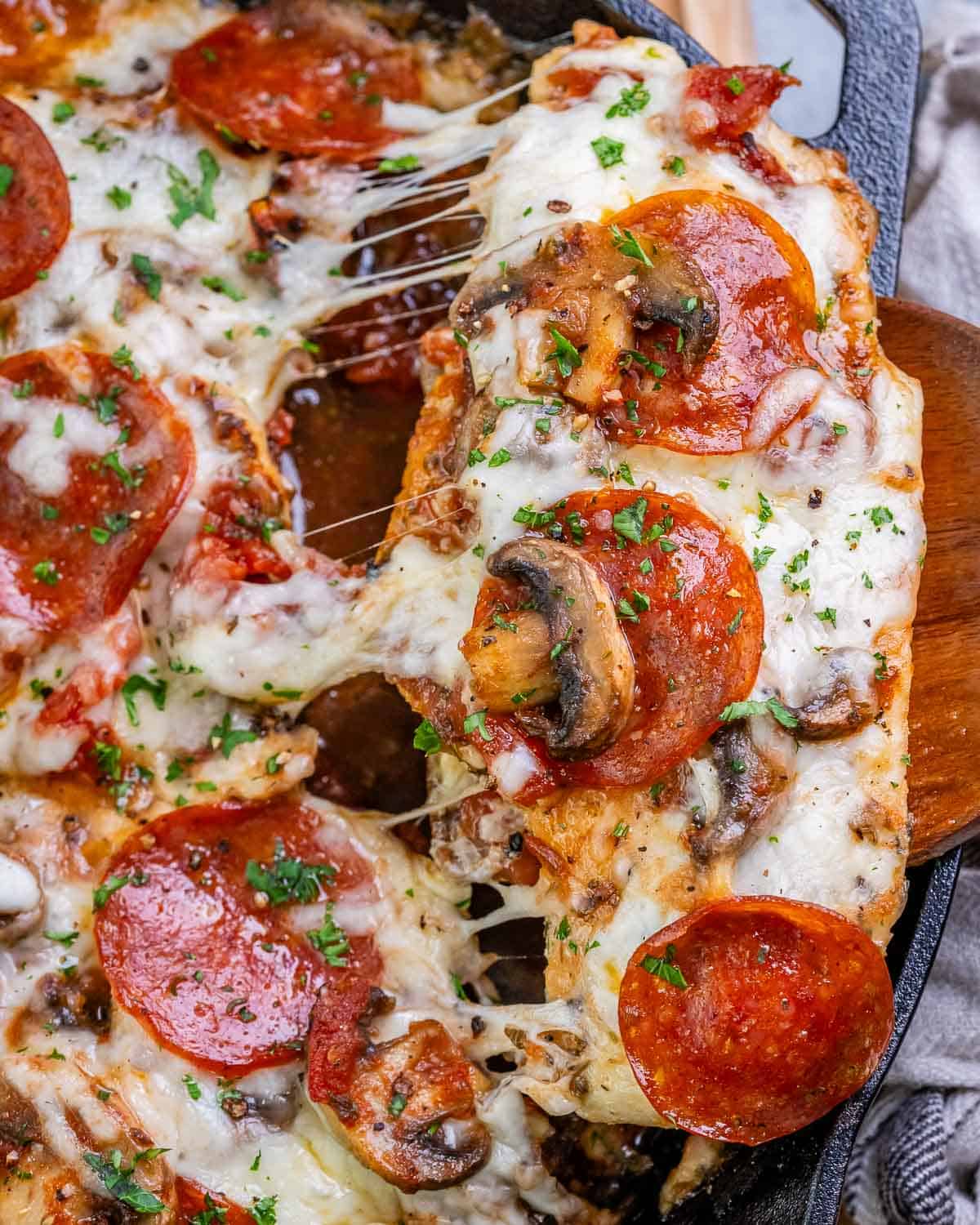 A close-up of chicken pizzaiola being lifted from the skillet.