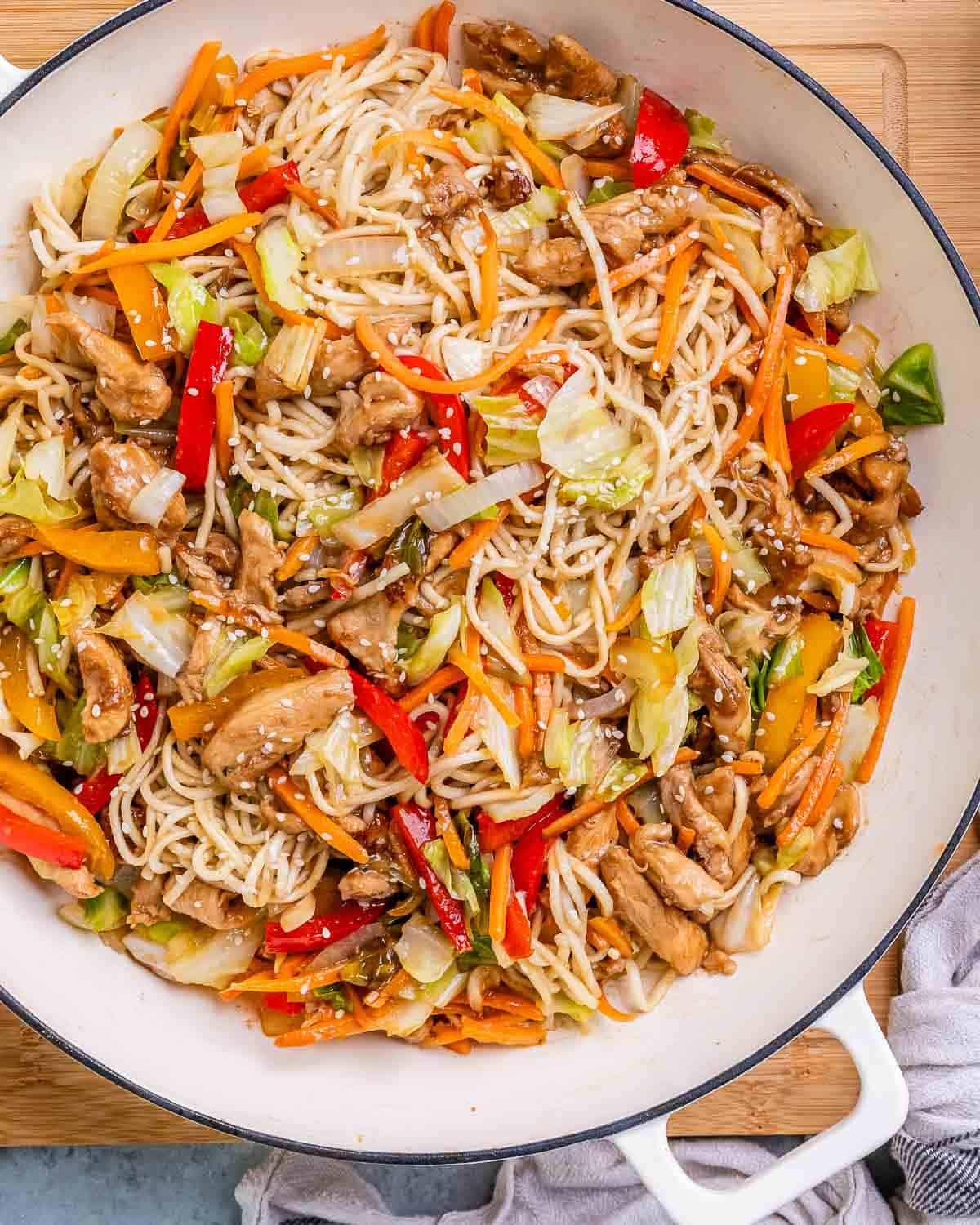 Chicken yakisoba in a white pan with cabbage and peppers.