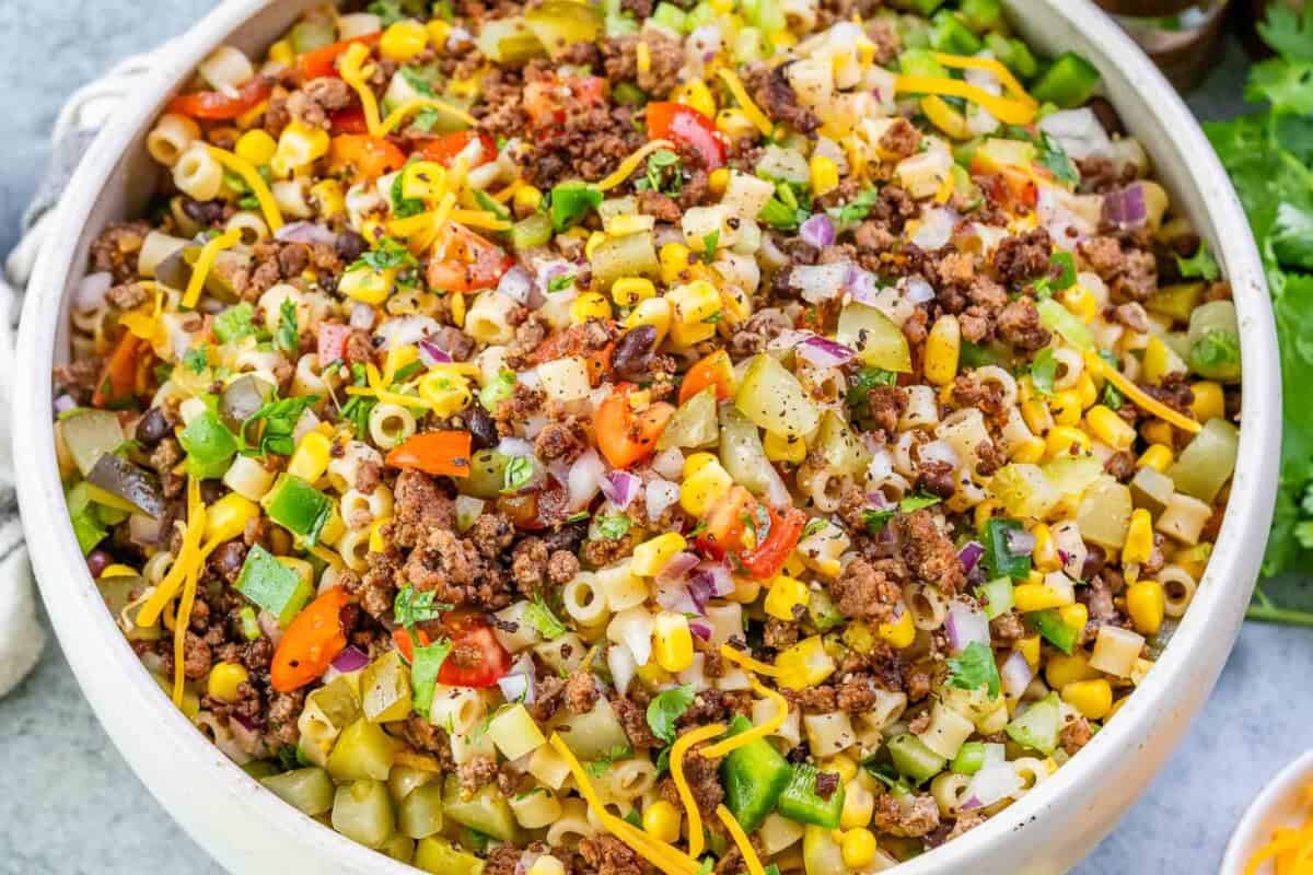 a bowl filled with cowboy pasta salad with pasta, ground beef, and veggies.