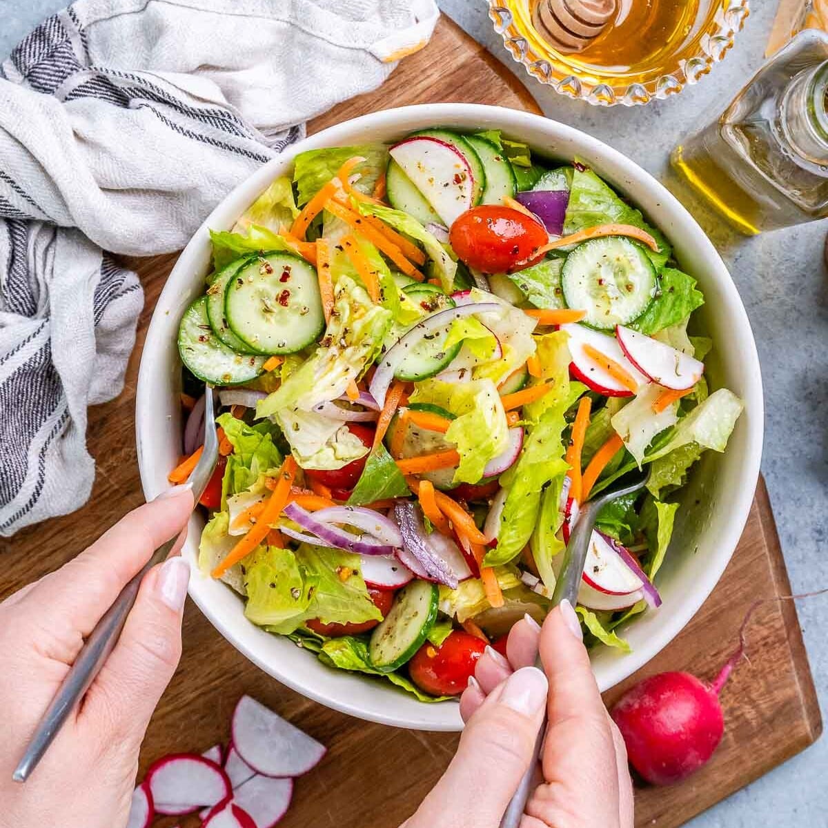 hand holding two forks to mix the salad in a bowl.