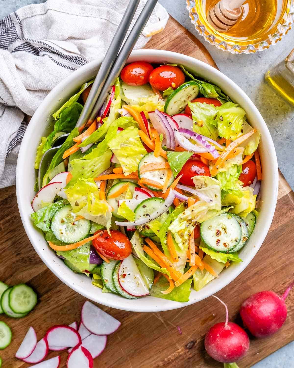 A white bowl of garden salad with tomatoes, radishes and cucumber.