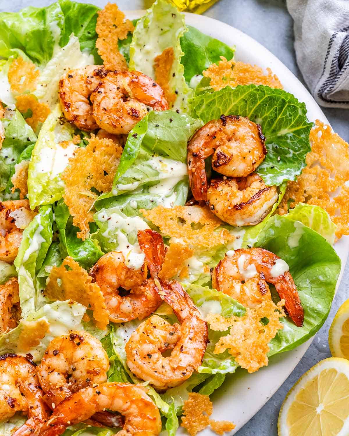 Shrimp Caesar salad with parmesan crisps on a white platter.