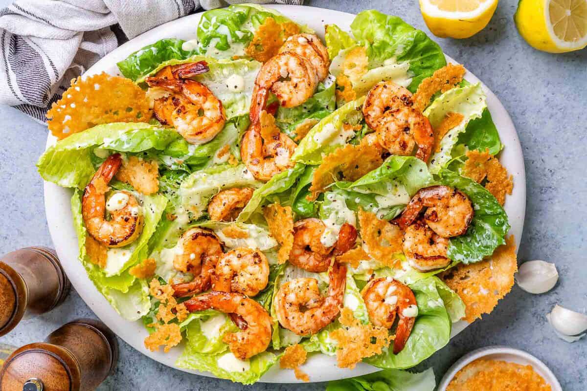 Caesar salad topped with shrimp in a dish.