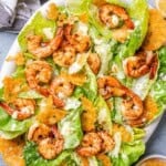 a plate filled with caesar salad topped with shrimp