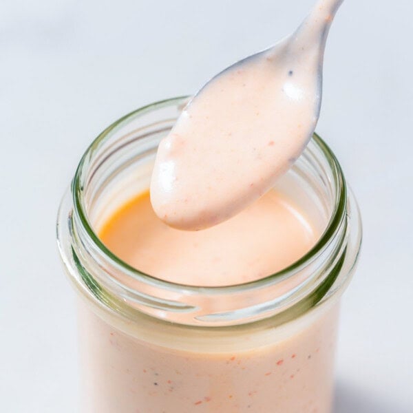 a jar filled with Bang Bang sauce with a spoonful of the sauce.